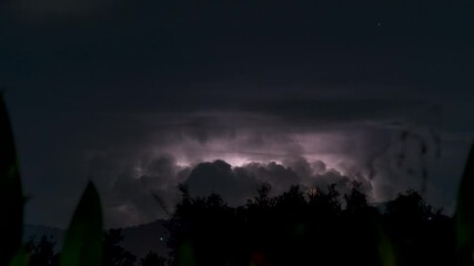 Multiple Lightning Strikes Illuminate Towering Thunderclouds Above Mountain Range at Night on a Tropical Island in Continuous Time-Lapse Sequence - Powered by Adobe