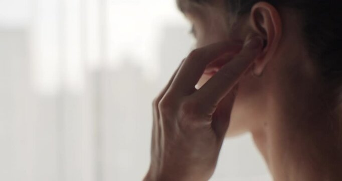 Woman inserts a wireless headphones into her ear close-up.