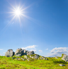 green mount top under a sparkle sun on blue cloudy sky