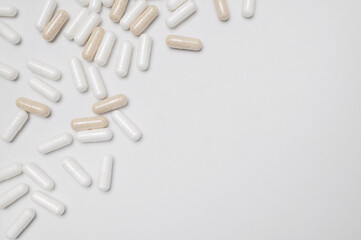 White and beige capsules vitamins, natural supplements, nutraceuticals on light gray background top view. Pattern of tablets, pills. Medical pharmaceutical background