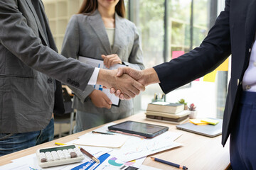 A group of people are working on a project and planning a business plan by sifting through documents and calculating budgets and exchanging information with each other. This scene shows teamwork
