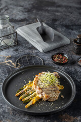 Sliced pork tenderloin with grilled asparagus and cheese sauce, garnished with microgreens