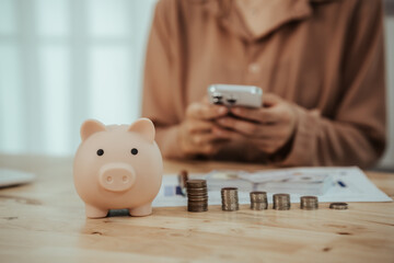 Close-up of woman putting coins into piggy bank, symbol of savings, financial growth, investment,...