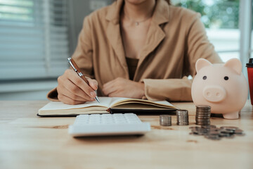 Close-up of woman putting coins into piggy bank, symbol of savings, financial growth, investment,...