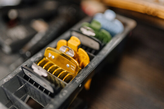 Close-up of colorful clipper guards arranged in a tray on a barber station, used for different haircut lengths in a professional barbershop setting..