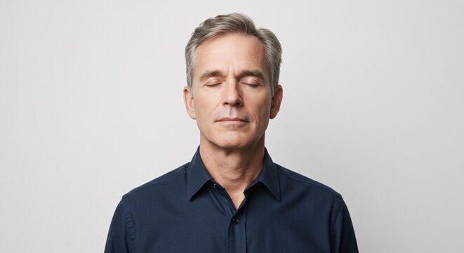Calm middle aged man with closed eyes meditating for mindfulness and well being