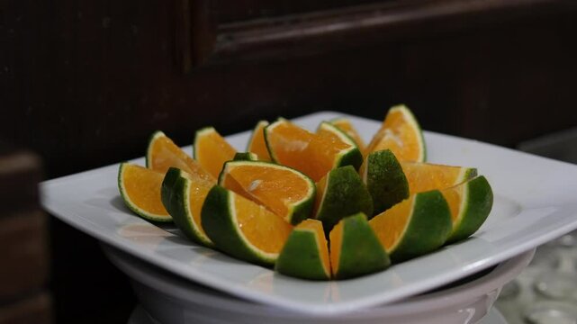 orange slices green Vietnamese oranges citrus fruits hanging on a branch, surrounded by glossy leaves. Captured outdoors in natural light, highlighting the vibrant and fresh details