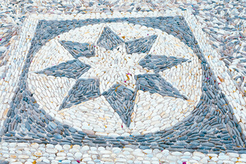 Intricate pebble mosaic design on a Mediterranean pathway in Plaka village, Milos island, Greece