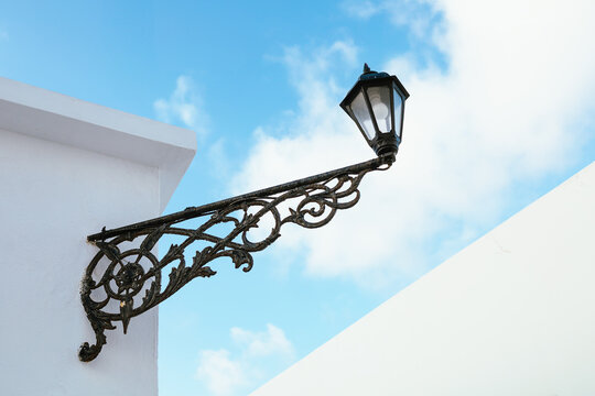 Ornate wrought iron lantern bracket on a whitewashed building in Plaka village, Milos island, Greece