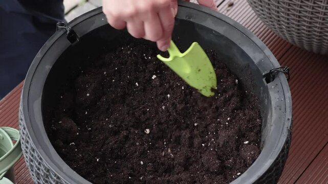 Woman mixing fertilizer and soil in pot in yard. Gardening and lifestyle in spring. Gardener tools.
