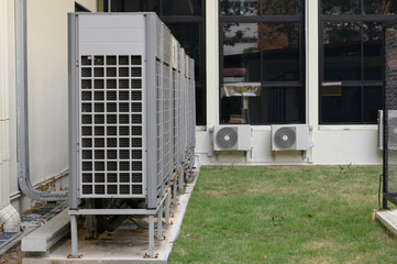 Air compressor or air condenser unit located on support outside building to heat released...