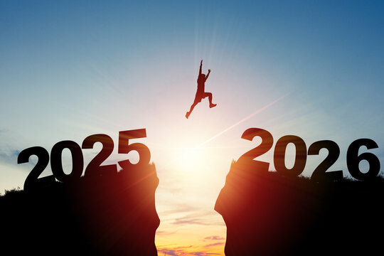 Welcome merry Christmas and happy new year in 2026,Silhouette Man jumping from 2025 cliff to 2026 cliff with cloud sky and sunlight.