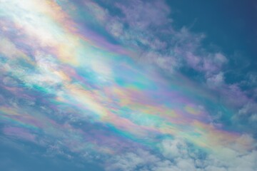 Iridescent cloud in blue sky, rare atmospheric phenomenon with pastel rainbow colors and sunlight diffraction in cirrus clouds