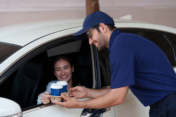 A woman picks up coffee, burgers and snacks in her car during rush hour from a drive-thru worker.