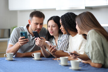 Four interracial friends checking their mobile phones