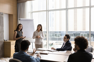 Teamwork. Two young female diverse ethnicities team leader business coach explain project structure by whiteboard engage multiracial office workers group in brainstorm discussion on meeting training