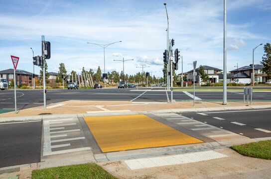 Wide suburban intersection with traffic signals, pedestrian crossings, speed bump and tactile paving in a newly developed Australian neighborhood. Contemporary urban planning, transport infrastructure