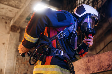 View from the side, with air balloons and mask. Firefighter in professional equipment is indoors in...