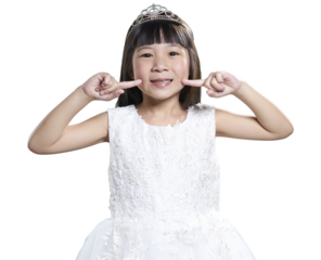 Smiling asian girl with crown pointing at cheeks on transparent background
