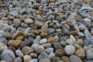 Smooth round pebbles texture background. Pebble sea beach close-up, dark wet pebble and gray dry pebble. natural gravel, texture from gravel. Gravel texture. Pebble stone background. Granite gravel
