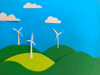 A handmade paper collage illustrates white wind turbines on rolling hills beneath a bright sky,...