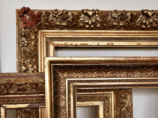 A collection of antique gold picture frames stacked in front of each other