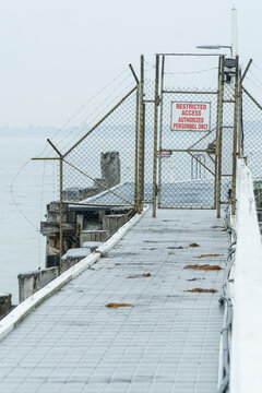 Looking along a seaside jetty to a locked gate and exclusion fencing