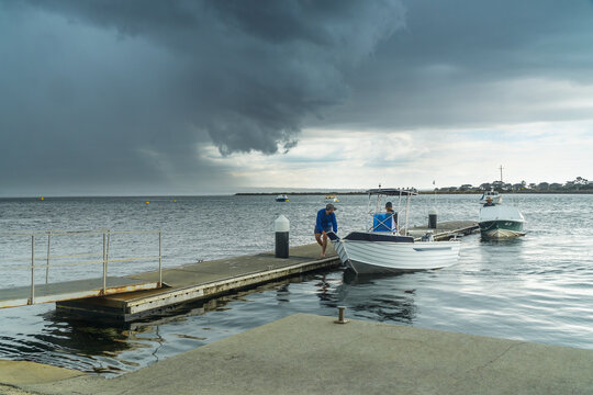 Men racing to get a boat tied to a jetty before a stormfront hits