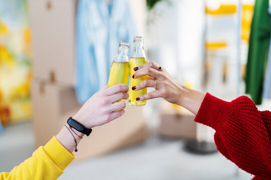 Hands of two people clinking bottles in a toast. They share a moment of celebration and relaxation after completing a task or moving.