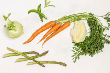 Spring carrots with green tops, green peas and savoy cabbage. Kohlrabi and lime on table
