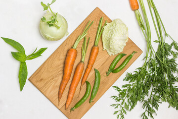 Spring carrots, green peas and savoy cabbage on cutting board.