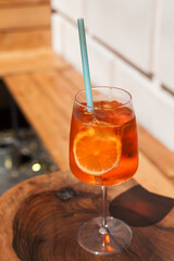 Refreshing Aperol Spritz cocktail in a woman's hand outdoors on a sunny day. Summer vibes with vibrant colors, natural textures, and a festive mood in the urban setting