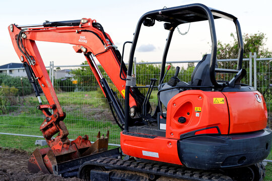 Mini digger standing idle at a construction site - red excavator