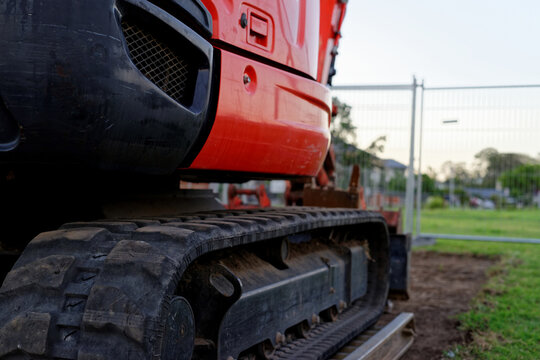 Mini digger standing idle at a construction site - red excavator