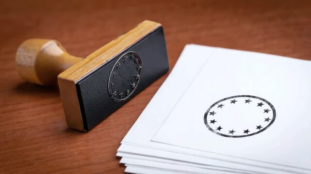 Rubber stamp with European Union stars and stamped papers on wooden surface for themes of official approval, documentation, administration, regulation, and EU institutional processes