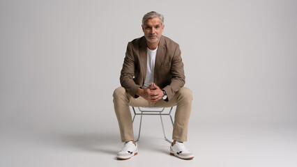 Happy middle aged business man sitting in chair isolated on white background. Happy mature businessman in his 40s