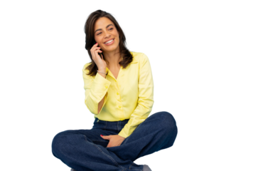 Young woman sitting cross-legged making a phone call, smiling and looking away, isolated on transparent background