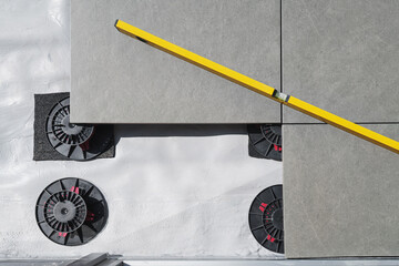 Laying tiles concept. Tiler, spatula and glue when laying tiles with close up hands. Stilts and...