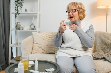 Obraz premium Sore throat. Senior woman uses throat spray at home