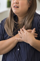 Panting and sick middle aged Asian woman suffering from heart condition, heart attack, irregular...