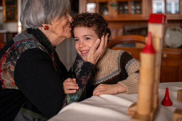 Grandmother kissing grandchild on forehead at home