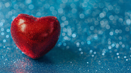 Fototapeta premium Sparkling red heart on shimmering blue glitter background. Valentine love concept. 
