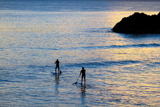 Two mature men paddleboard SUP near Norries Head at Cabarita Beach, NSW