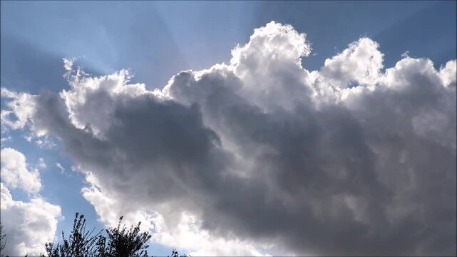 Big gray cloud, cloud covered the sun against the blue sky on a spring day, glow through the cloud - horizontal video