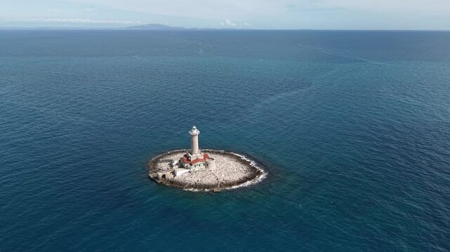 A majestic Porer Lighthouse stands proudly on a rocky island off Istria&rsquo;s coast, with its red-roofed buildings and tall stone tower. Adriatic coastline, Croatia