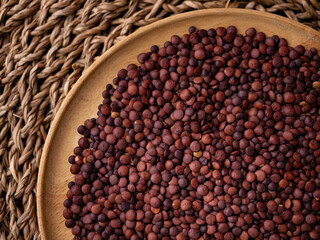 Organic uncooked seeds dark red brown lentils.