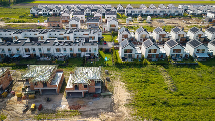 Rows of single-family houses on the city outskirts, featuring solar panels and green gardens,...