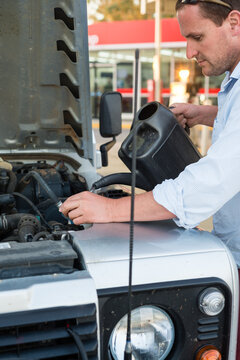 man checking fluids in his car at the fuel station