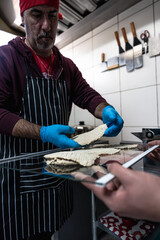 Mature man placing breaded meat fillets on tray – small food business and culinary production