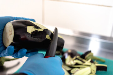 Chef peeling eggplant with vegetable peeler in professional kitchen